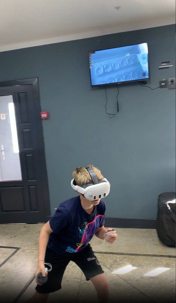 Іменинник задуває свічки на торті. Він святкує свій день народження в нашому клубі. Вересень 2023 року, Харків. Клуб віртуальної реальності.